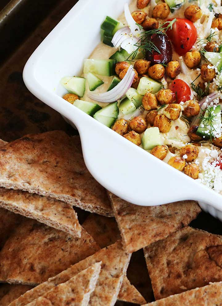 Loaded greek hummus in dish with pita