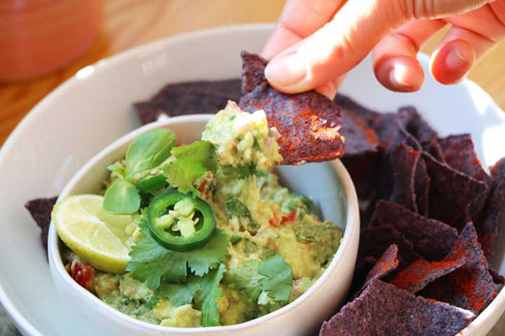 Dipping tortilla chips in guacamole verde
