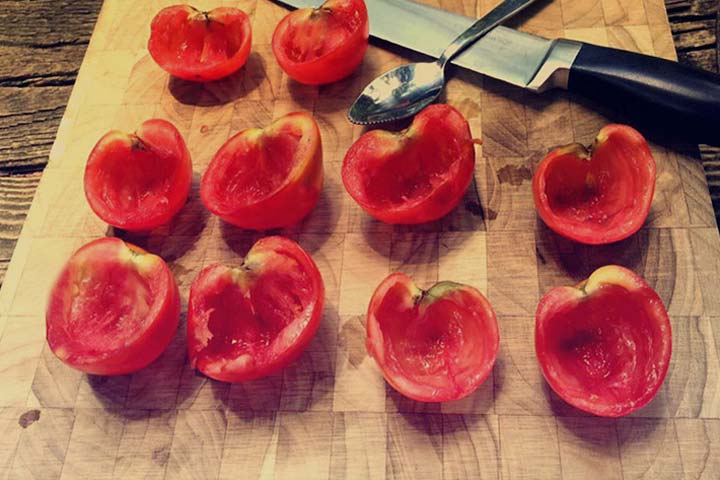 Tomatoes scooped out lined up on cutting board 