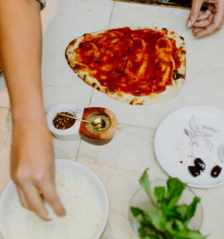 Spreading cheese on pizza