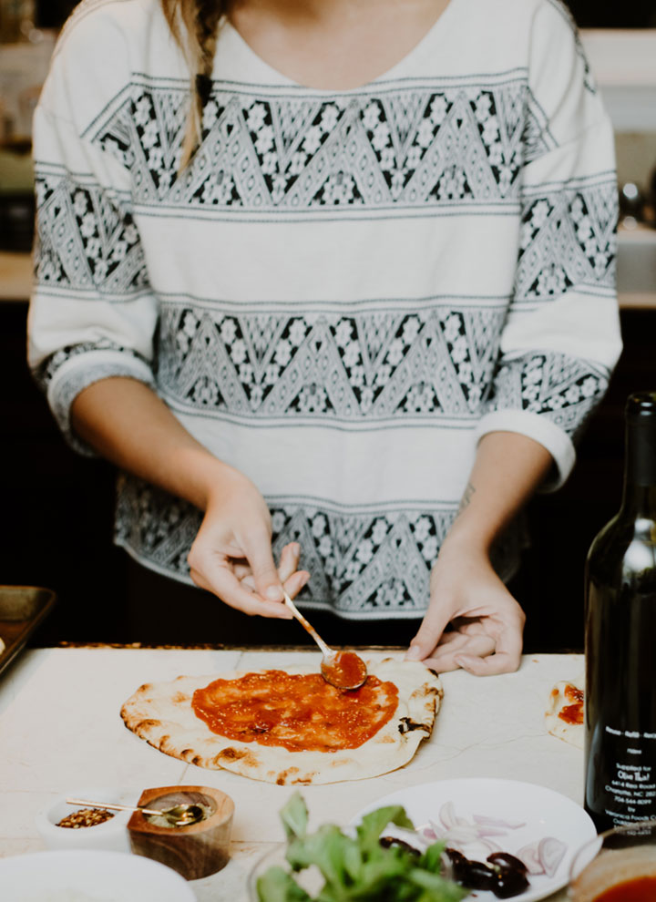 spreading tomato sauce on pizza